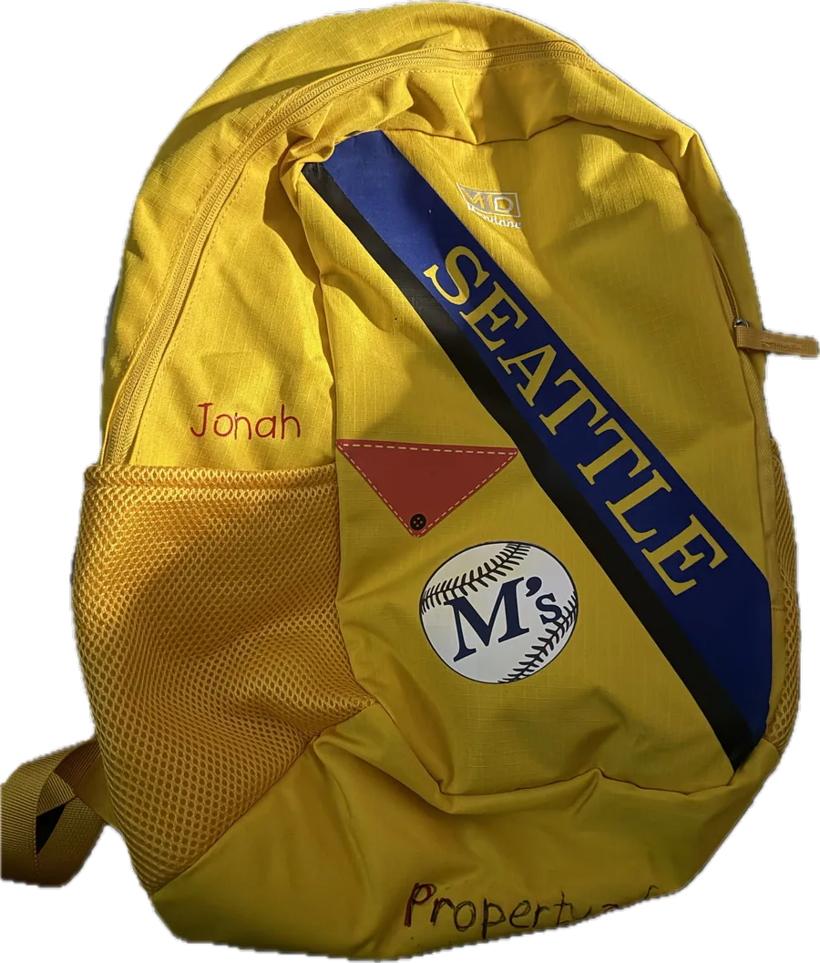 A yellow backpack built as part of a child's Halloween costume, personalized with a name and a Seattle Mariners baseball design.